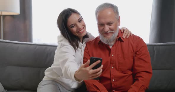 Cheerful Young Adult Grownup Granddaughter Laughing Watching Funny Social Media Videos Using Smart