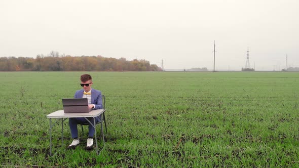 Around Drone Fly View of Young Man Working Remotely with Laptop Outside Alone Isolated on Spring alt