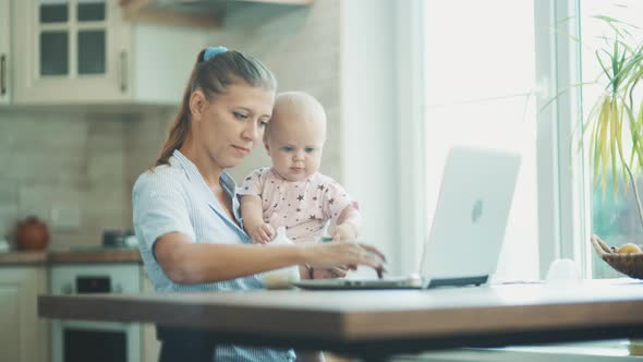 Woman With A Little Child Up To A Year Old At Home In The Kitchen alt
