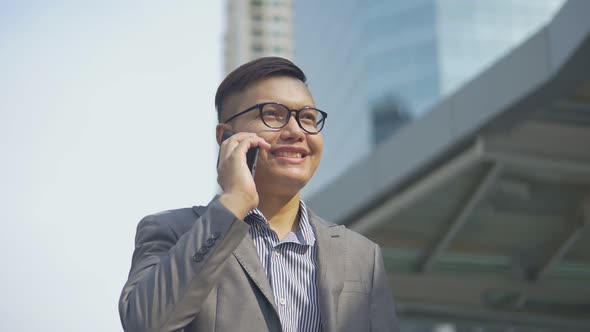 Portrait handsome Asian businessman talking phone with friend walking on urban city.