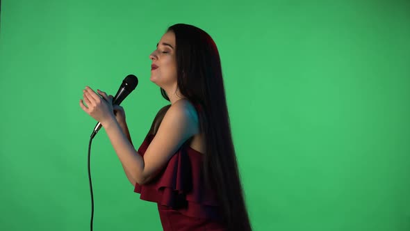 Portrait of Beautiful Young Woman Illuminated By Blue Neon Light Sings Song Into Microphone alt
