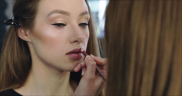 Closeup of Girl with Perfect Nude Makeup and Makeup Artist alt
