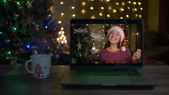 Happy Woman with Sparklers Congratulates Relatives on Christmas Via Laptop Online