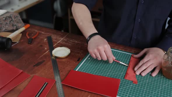Leathersmith is Applying Glue on a Leather Parts of the Zipper with a Special Brush alt