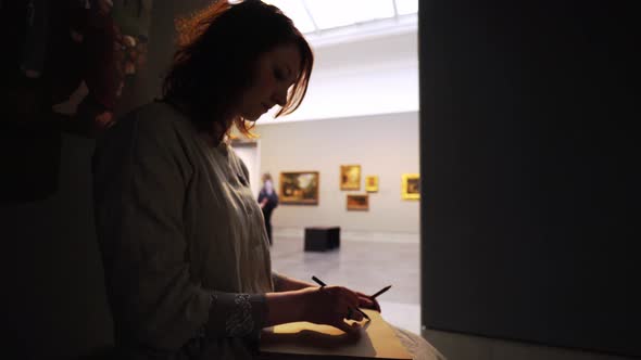 Artist Draws Sketches in Notebook in Art Museum