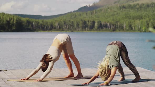 Two Young Women Practicing Vinyasa Yoga in Nature alt