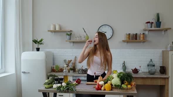 Pretty Young Girl Coming To the Table with Juicy Apple. Cutting with Knife and Eating Fresh Fruit alt