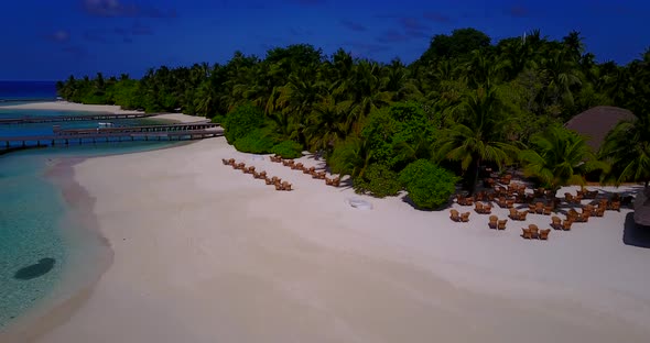Wide fly over travel shot of a sunshine white sandy paradise beach and blue water background in hi r alt