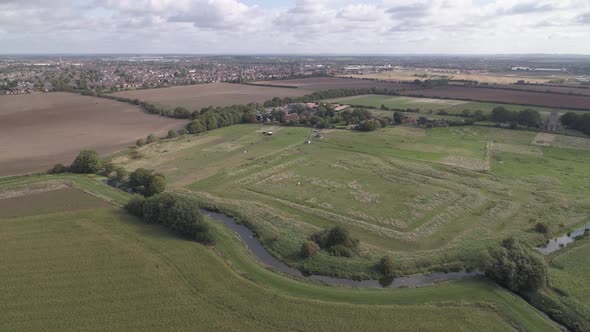 Aerial pan shot of fields and farms with a river cutting through them. alt