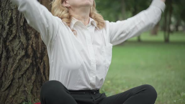 Unrecognizable Caucasian Blond Businesswoman Sitting in Lotus Pose on Summer Meadow in Park alt