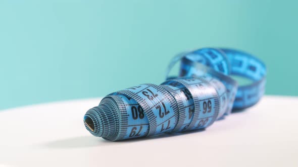 Close Up of a Blue Measure Tape on Colored Rotating Background Rotation Reflection