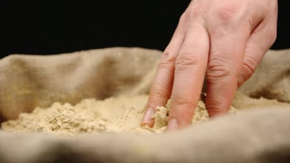 Human hand touching a ginger powder in a sac
