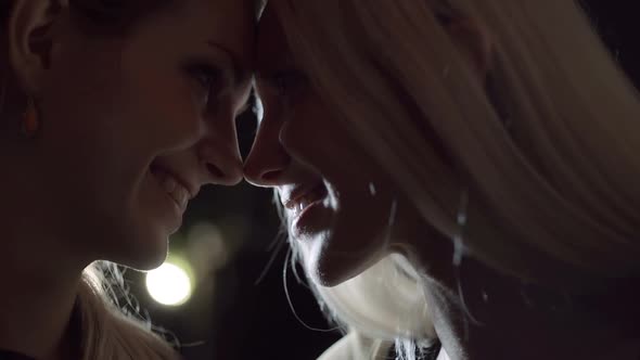 Close Up of Young Beautiful Homosexual Lesbian Woman Couple with Teasing Smile at Night Slow Motion
