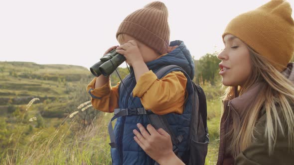 Cute Boy with Binoculars and Mother Enjoying Scenic View alt