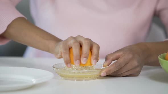 Woman Juicing out Orange with Handheld Juicer, Taking Care of Health, Nutrition alt