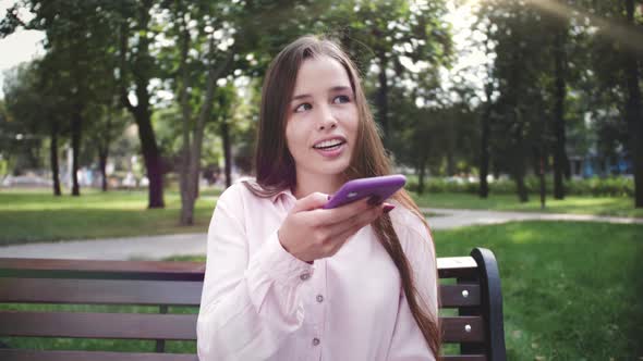 Young Woman Holds Smartphone Using the Voice Recognition Ai Audio Message Speech Helper Chatting alt