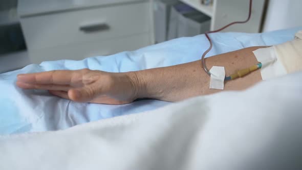 Mature Woman Under Dropper Suffering From Terrible Pain, Holding Mattress