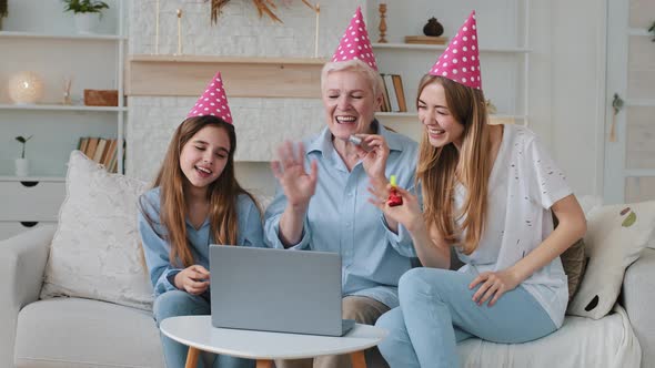 Cute Child Daughter Young Adult Mother and Old Grandma Looking at Laptop Screen Wearing Party Hats alt