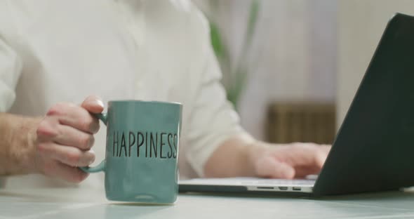 Man Working on Laptop and Drinking Coffee