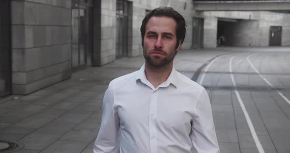 Young Stylish Bearded Business Man Walks Down Business District in White Shirt on Urban Background alt