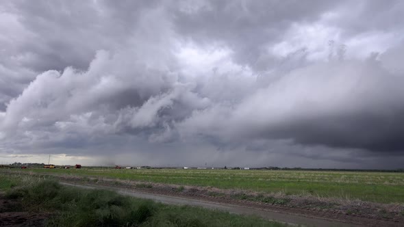 Severe storm clouds rolling in the sky as tornado forms in the background alt