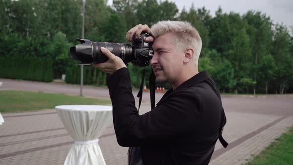 Male Photographer Takes Photos on a Professional Camera Outdoors at Event