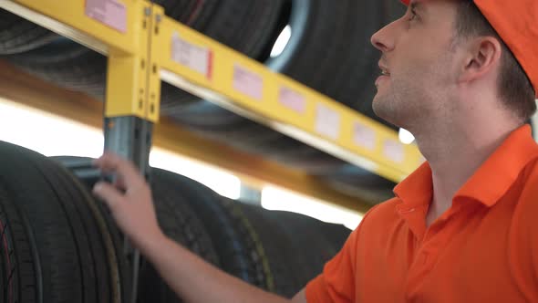 technician service person working in garage car to recommend and sell a tire on shelf storage alt