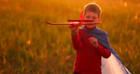 Boy Playing in the Field with a Plane in His Hands at Sunset alt
