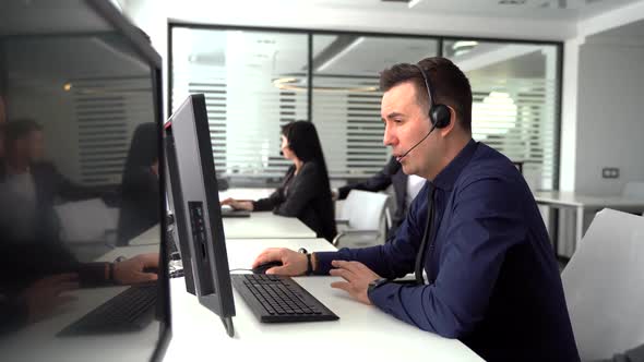 Handsome Male Customer Service Agent Working in Call Center Office As a Telemarketer.