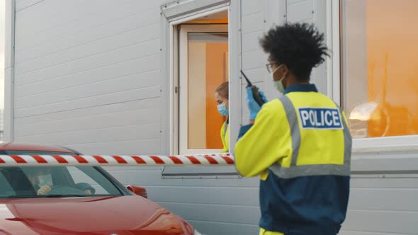 Driver in Mask Showing Document To Traffic Checkpoint Worker in Booth alt
