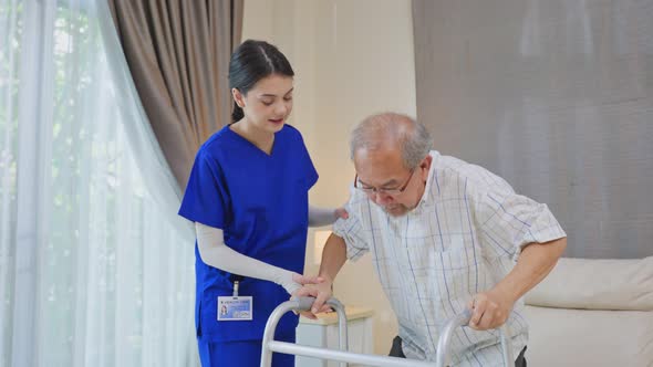 Asian Senior elderly disabled man patient walking slowly with walker at nursing home care. alt