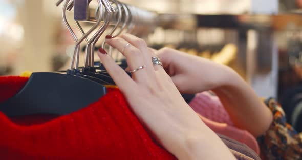 Close Up of Woman Looking Through Clothes on a Rail in Shopping Mall alt