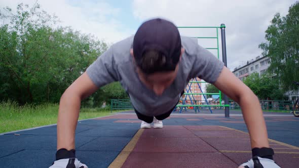Young Guy Performs Pushup Exercises on the Street a Sports Ground alt