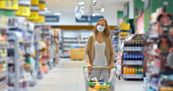 Young Woman Carries a Cart with Groceries in the Supermarket, Shopping for Groceries During the alt