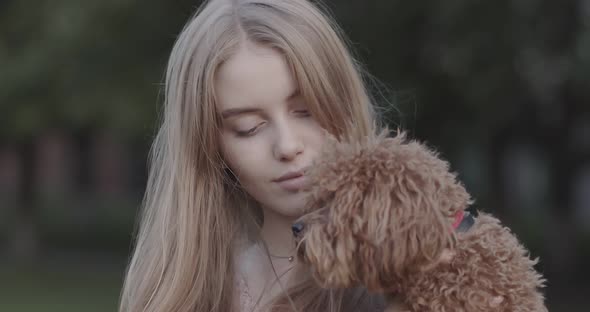 Beautiful young girl holding a dog in her arms