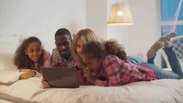 Happy Family and Girls Sharing Tablet Pc on Bed alt