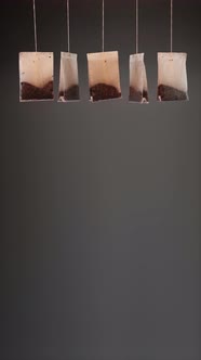 Tea Bags Hanging on Dark Background alt