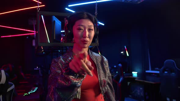 Cute Asian Girl in a Computer Club Puts on a Headset and Calls with Her Finger to Join Her alt