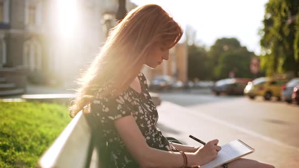 Foxy Dreamy Young Girl Sitting Writing Notes with Sunlight on Hair in Slowmotion alt