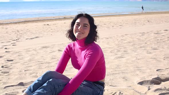 Young Woman Smiling on the Beach Against the Background of the Seascape alt