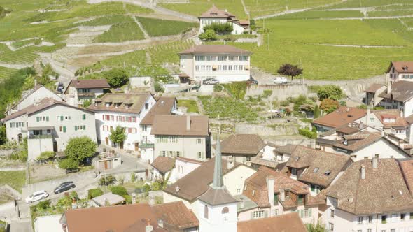 Aerial orbit around bell tower of typical village (Riex) in Lavaux vineyard - Switzerland alt