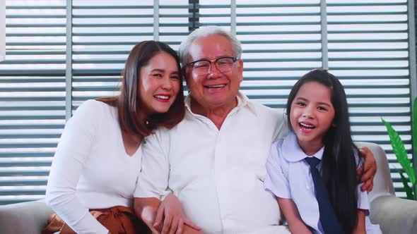 Happy family with grandfather, mother and little daughter spending time together in living room. alt