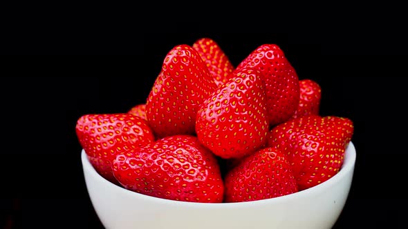 Strawberries without tails lie in white bowl or plate. It rotates alt
