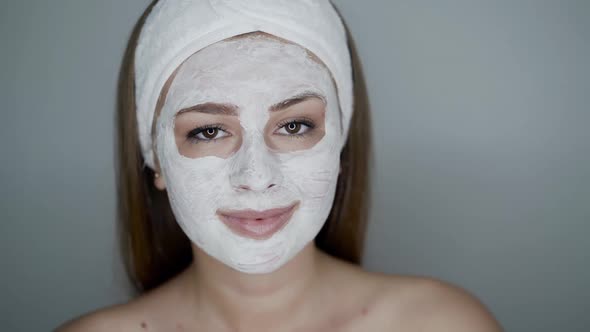 Girl with Cosmetic Mask on Face Looks at Camera and Down on Naked Shoulder alt