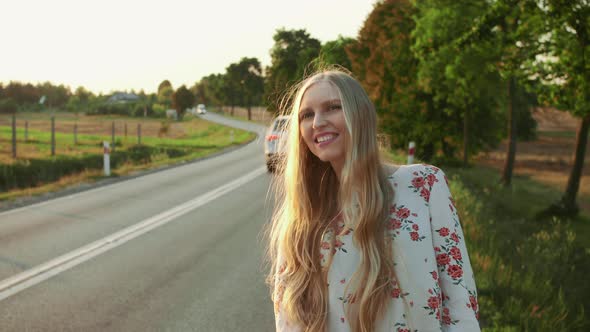 Traveler Woman Hitchhiking on a Sunny Road and Walking alt