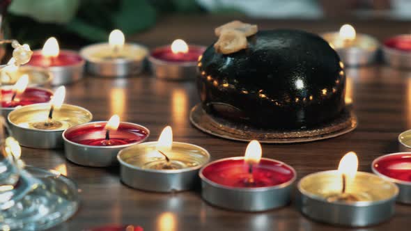 Closeup of Mousse Cake Glasse Next To Candles Burning in the Shape of a Heart