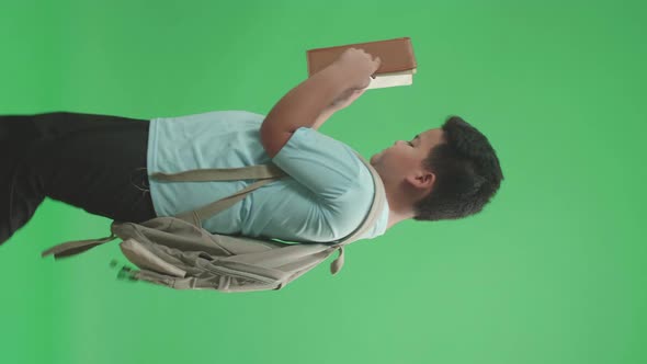 Side View Of Asian Boy Student Holding And Looking Book While Walking To School On Green Screen alt