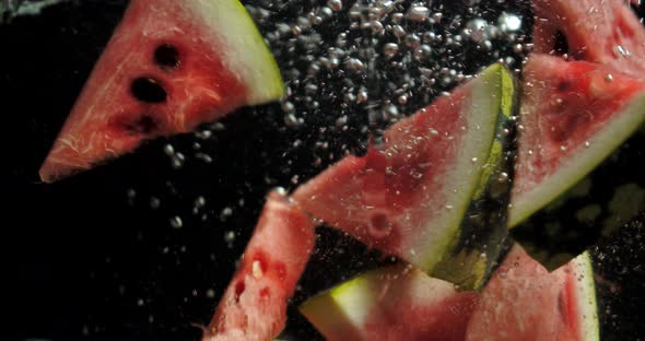 Pieces of Watermelon Fall Under Water with Air Bubbles.  alt