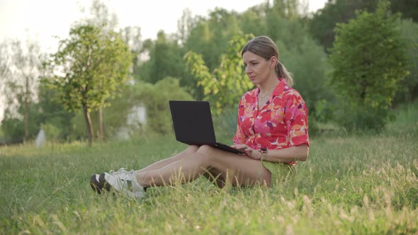 Business Woman Working Remotely in the Park Using a Laptop