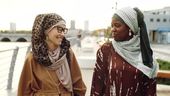 Young Muslim Women Walking on Embankment alt